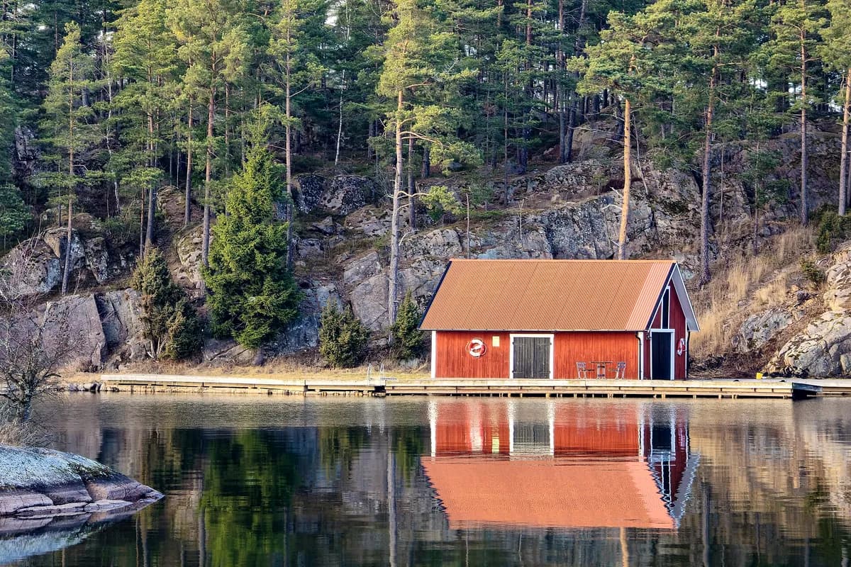 Röd sjöbod speglad i stilla vatten